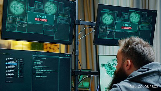 Ein Mann sitzt vor mehreren Computer-Monitoren, auf denen "Zugriff verweigert" zu lesen ist.