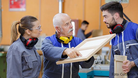 Junge Auszubildende im Schreinerhandwerk im Gespräch mit ihrem Ausbilder.