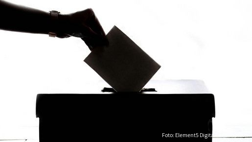 Ein Wahlschein wird in die Wahlurne eingeworfen
