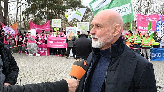 Das Foto zeigt Impressionen von der Demonstration in Potsdam vor Beginn der dritten Verhandlungsrunde am 14.3.2025: Zu sehen sind Demonstrierende mit Fahnen und Plakaten sowie Vertreter der Gewerkschaften, die Reden halten.